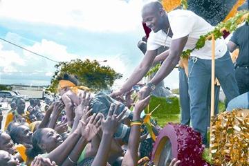 Beijing Olympic relay gold medal winner Asafa Powell is handed a baby by some one in the crowd during Friday’s national parade in Kingston (Paul Reid)