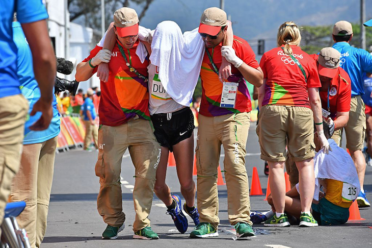 Evan Dunfee is helped off the course after finishing fourth at the Rio Olympics ()